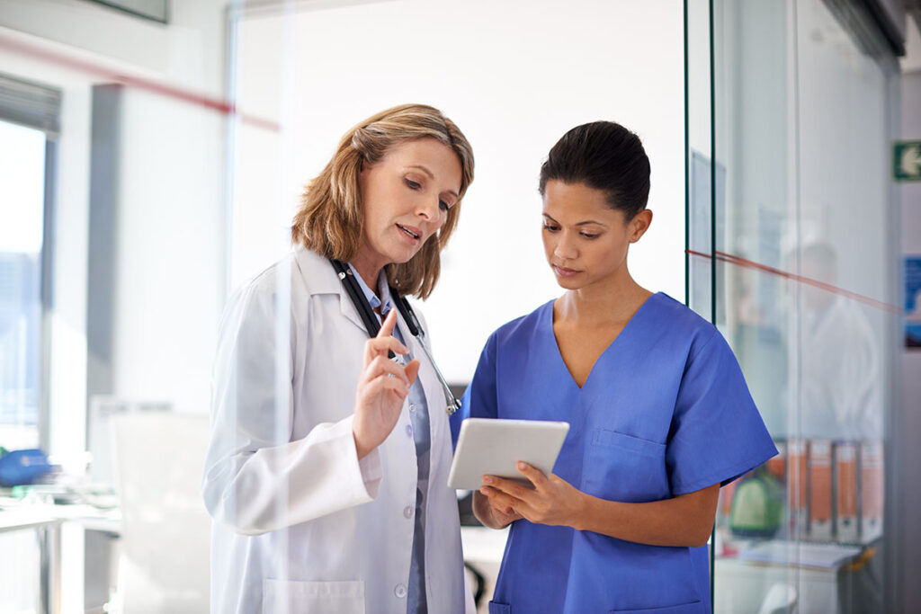 two medical professionals stand together and look at a tablet