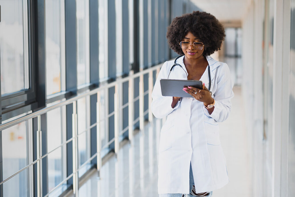 woman medical professional with glasses walks and types on tablet