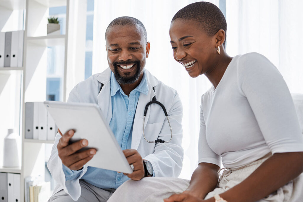 medical professional holds a tablet smiling and showing patient their information