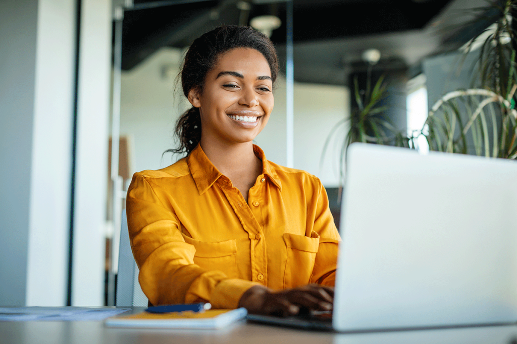 Smiling woman using laptop to research what is a behavioral health provider