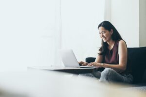 female behavioral healthcare professioal smiling as she works at laptop to schedule a demo for behavioral healtcare software