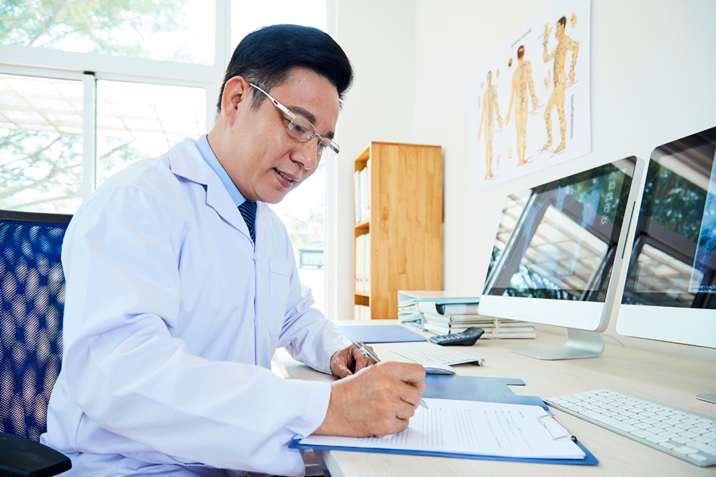 doctor seated at workstation reviewing tips on choosing EMR software for your company.