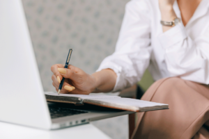 close up of behavioral health professional taking notes from a laptop on the features of electronic medical record sofware for MAT clinics.