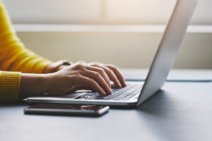 close up of a medical professional typing on a laptop and exploring the difference between an EMR vs. EHR.