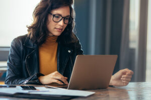 young female healthcare professional working at a laptop leveraging AI to improve RCM.