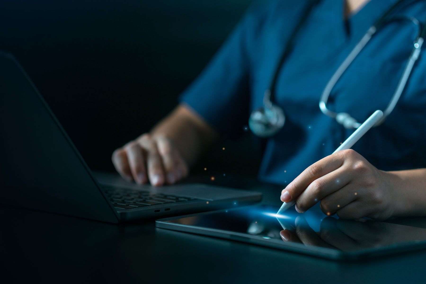 close up of a medical professional wearing a stethoscope as they sit at a desk wondering do electronic medical records improve quality of care?
