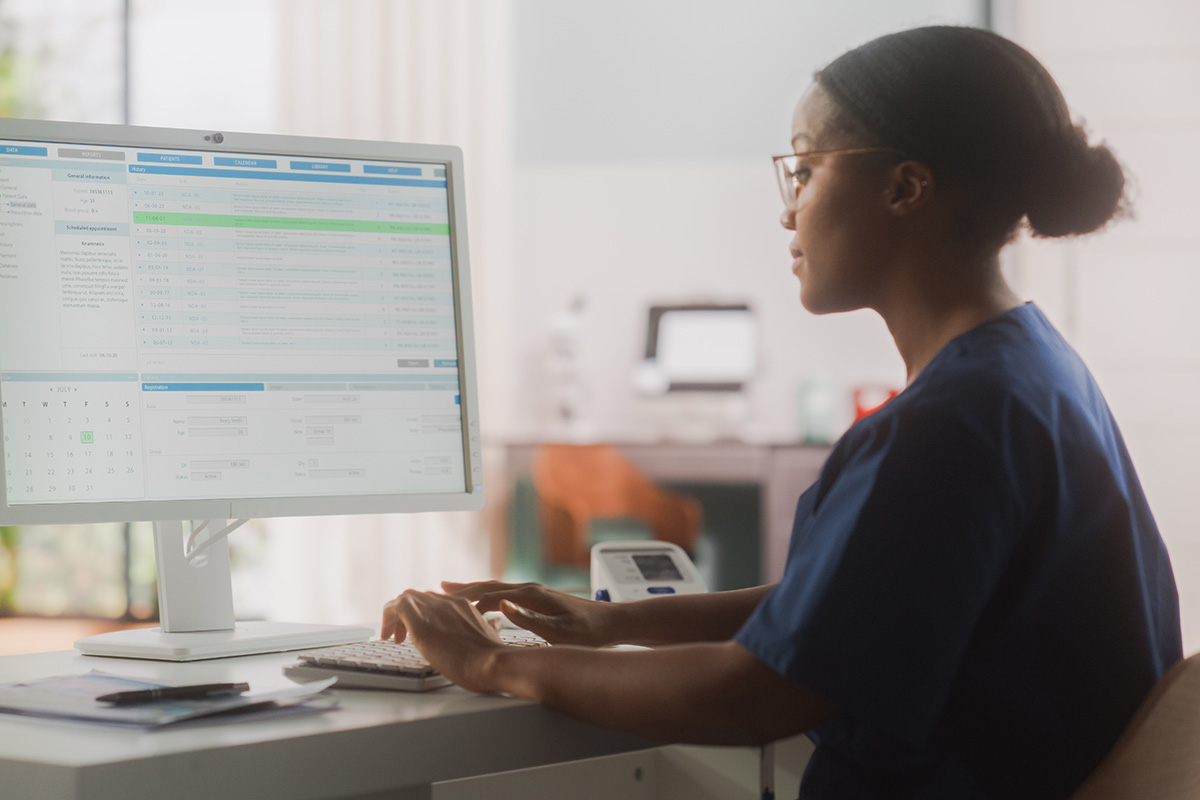 healthcare worker seated at desk in an office working at a terminal and boosting behavioral health billing efficiency with EMR automation.