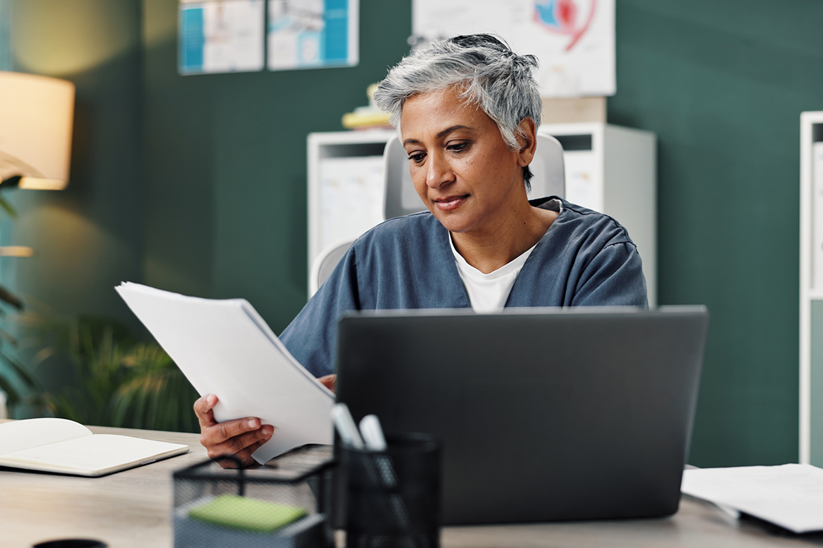 healthcare professional handling a thick medical chart and considering transitioning from paper to electronic medical records