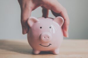 Hand holding smiling piggy bank indicating the question: how much does EMR software cost for a small practice
